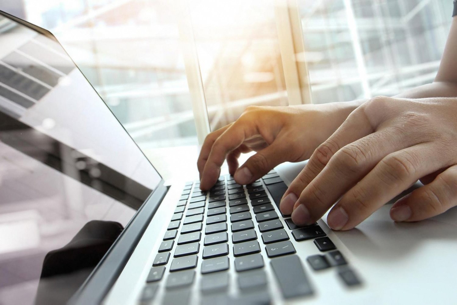 Employee typing on a laptop in a bright UAE office where the local server is slowing work down
